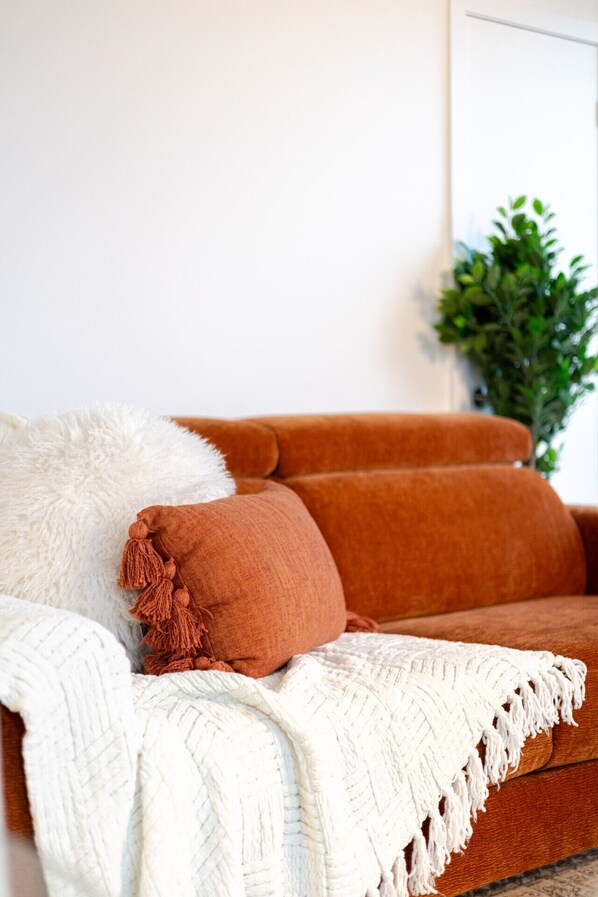 A brown sofa with a white throw blanket and a brown cushion. - City Comfort – Free Parking (Montreal)