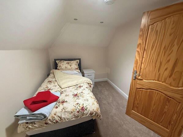 A bedroom with a bed, a nightstand, a wooden wardrobe, and a ceiling light. - Lymington Seaside Cottage Retreat (Lymington)