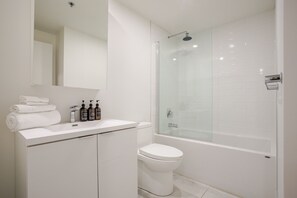 Et moderne badeværelse med en brusekabine med glasdøre, en hvid vask og et toilet.