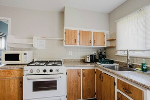 Una cocina con electrodomésticos blancos, armarios de madera y encimera de granito.