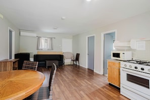 A compact kitchen with a microwave, stove, and wooden cabinets.