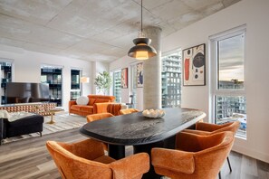 Un salon moderne avec une grande télévision, des meubles orange et une table à manger avec des chaises.