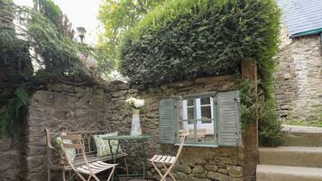 A stone wall with a window, a bench, and a table with chairs.