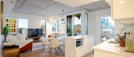 A modern living room with a TV, seating, and a city view.