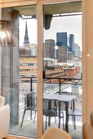 Een balkon met uitzicht op de stad, inclusief een kerktoren en moderne gebouwen.