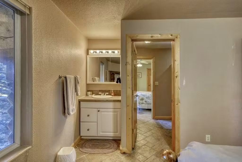 A bathroom with a vanity, mirror, and a window.