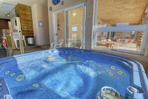 Un bain à remous doté d’une enceinte en verre, d’un mur en bois et offrant une vue sur le mobilier d’extérieur.
