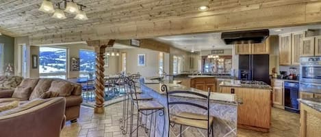 Ampla sala de estar com lareira, sala de jantar com ilha central e cozinha equipada com eletrodomésticos modernos.
