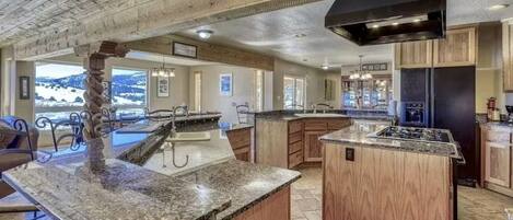 A spacious kitchen with granite countertops, wooden cabinets, and a large island.