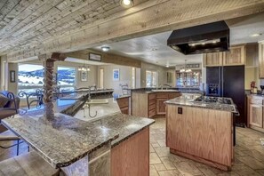 Une cuisine spacieuse dotée de plans de travail en granit, d’armoires en bois et d’un grand îlot central.