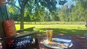A wooden deck with a bench and a small table, a cup, and a magazine.