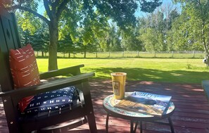 Une terrasse en bois avec un banc et une petite table, une tasse et un magazine.