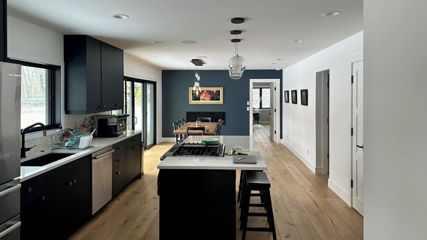 A modern kitchen with a central island, dark cabinetry, and recessed lighting.