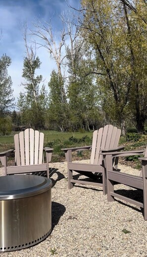 An outdoor seating area with Adirondack chairs and a metal fire pit.