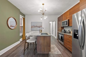 A modern kitchen with a central island, stainless steel appliances, and a contemporary light fixture. - Hot Tub - Sleeps 9 - Near OSU (Columbus)