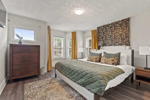 Ein Schlafzimmer mit einem Bett, einem Schminktisch, einem Fenster und einem Vorhang.