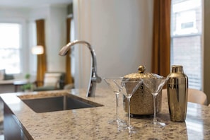 A kitchen counter with a sink, a decorative container, and a cocktail shaker. - Hot Tub - Sleeps 9 - Near OSU (Columbus)