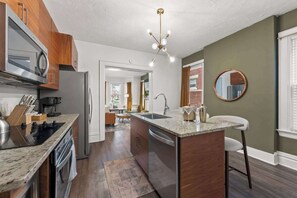 A modern kitchen with a central island, stainless steel appliances, and a view to the dining area. - Hot Tub - Sleeps 9 - Near OSU (Columbus)