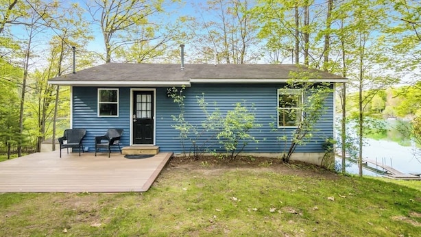 Une maison de plain-pied avec une terrasse, un petit porche et une vue sur un lac.