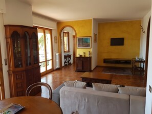 Ein Wohnzimmer mit einer Couch, einem Holzschrank und einem an der Wand befestigten Fernseher.