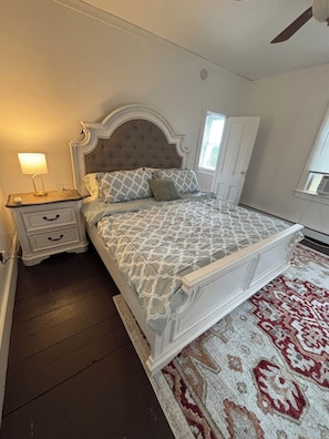 Un dormitorio con cama, mesita de noche, lámpara y una alfombra estampada.