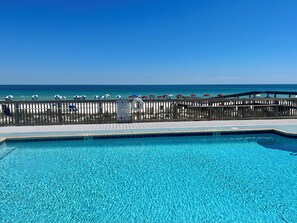 A clear blue pool with a wooden deck and a view of the beach. - Oceanfront Condo, Gated Entry, Pool, King Bed, <100 Steps to Sand. (Pensacola)