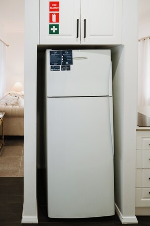 A white refrigerator with a freezer compartment, located in a kitchen with white cabinets. - Ash Cottage Intimate Wine Country Living for Two (Mudgee)