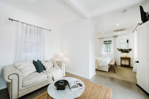 A modern living room with a sofa, a coffee table, and a lamp. There is a door leading to another room. - Ash Cottage Intimate Wine Country Living for Two (Mudgee)
