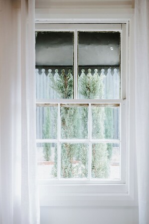 A window with a white frame and frosted glass panes, offering a view of greenery outside. - Ash Cottage Intimate Wine Country Living for Two (Mudgee)