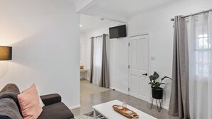 A modern living room with a sofa, a coffee table, a TV, and a potted plant.