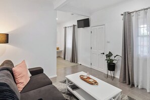 A modern living room with a sofa, a coffee table, a TV, and a potted plant.