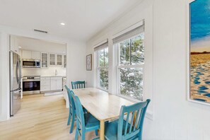 Una cocina moderna con armarios blancos, una mesa de comedor de madera y sillas azules.