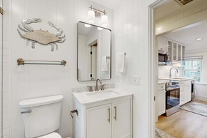 Un baño con inodoro, lavamanos, espejo, toallero y una pieza decorativa de un cangrejo en la pared.