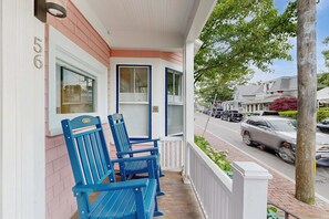 A porch with blue chairs, a white door, and a brick wall.