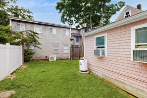 Ein Wohngrundstück mit Rasen, einem weißen Propangasbehälter und einem rosa Haus mit weißem Zaun.