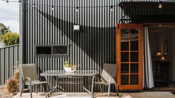 A patio with a table and chairs, a potted plant, and a door leading to an interior space.
