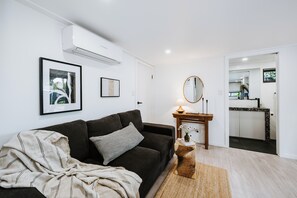 A modern living room with a dark sofa, a framed picture, and a small table with a lamp and vase. - Luxe Loft Contemporary Comfort by Mudgees CBD (Mudgee)