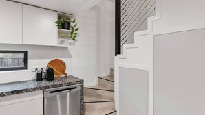 Una cocina moderna con armarios blancos, encimera de granito y lavavajillas de acero inoxidable.