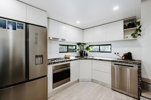 A modern kitchen with stainless steel appliances, a built-in oven, and a dishwasher. - Luxe Loft Contemporary Comfort by Mudgees CBD (Mudgee)