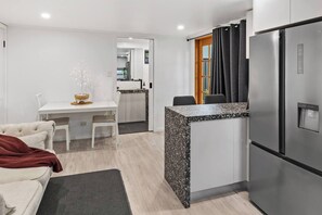 Eine kompakte Küche mit Kühlschrank, einem Esstisch mit Stühlen und einer kleinen Sitzecke mit einer Couch.