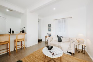 A modern living room with a sofa, coffee table, and a dining area with chairs and a small table. - Claret on Douro Three Cottages for Group Getaways (Mudgee)