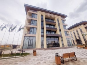 A multi-story hotel with a prominent entrance, a covered outdoor area, and a flag display.
