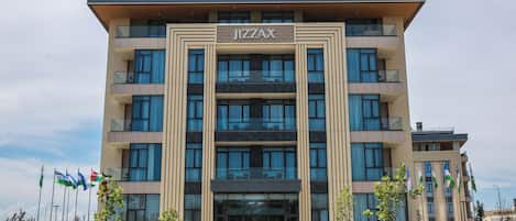 A multi-story building with a prominent 'JIZZAX' sign, large windows, and a flat roof.