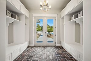 A hallway with a brick-patterned floor, white walls, and a double door leading outside. - PRIVATE 16+HiddenOasis! SwimPond+HotTub+Sauna+2Firepits+10ac, Pets Welcome! (Hampstead)