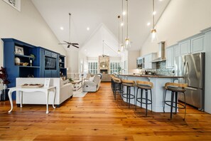 A spacious kitchen with a central island, bar stools, and a ceiling fan. - PRIVATE 16+HiddenOasis! SwimPond+HotTub+Sauna+2Firepits+10ac, Pets Welcome! (Hampstead)