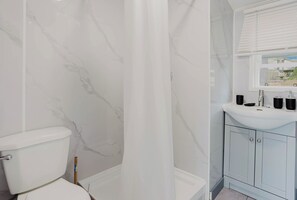 A bathroom with a toilet, a shower curtain, a sink with a mirror, and cabinets.