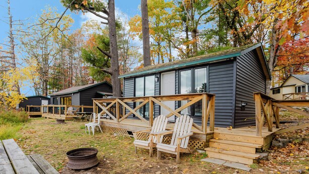 Une cabane dotée d’une terrasse, de meubles de jardin et d’un foyer extérieur.
