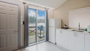 A modern kitchen with a refrigerator, sink, and window overlooking a deck. - 1 Bedroom Cottage IX: PL (Gravenhurst)
