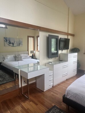 A bedroom with a bed, a desk, a dresser, a television, and a mirror. -  Greyhawk on Blueberry Hill —  2 bdrm 2 bath with private balcony (Whistler)