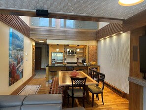 A modern kitchen with a central island, wooden flooring, and a dining area with a bench and chairs. -  Greyhawk on Blueberry Hill —  2 bdrm 2 bath with private balcony (Whistler)